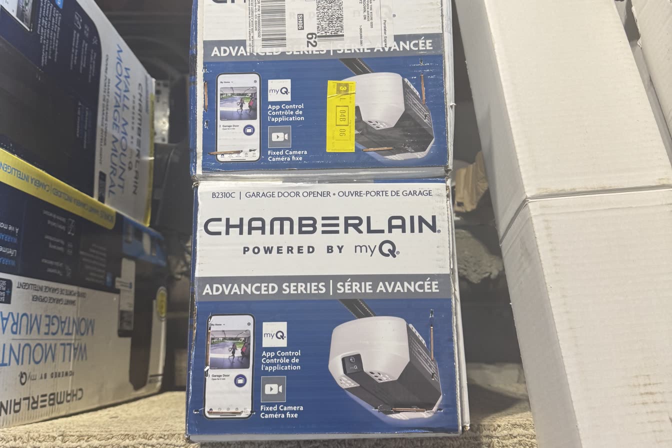 Two boxed Chamberlain Advanced Series wall-mount garage door openers on a shop shelf, labelled with myQ app control and a built-in camera