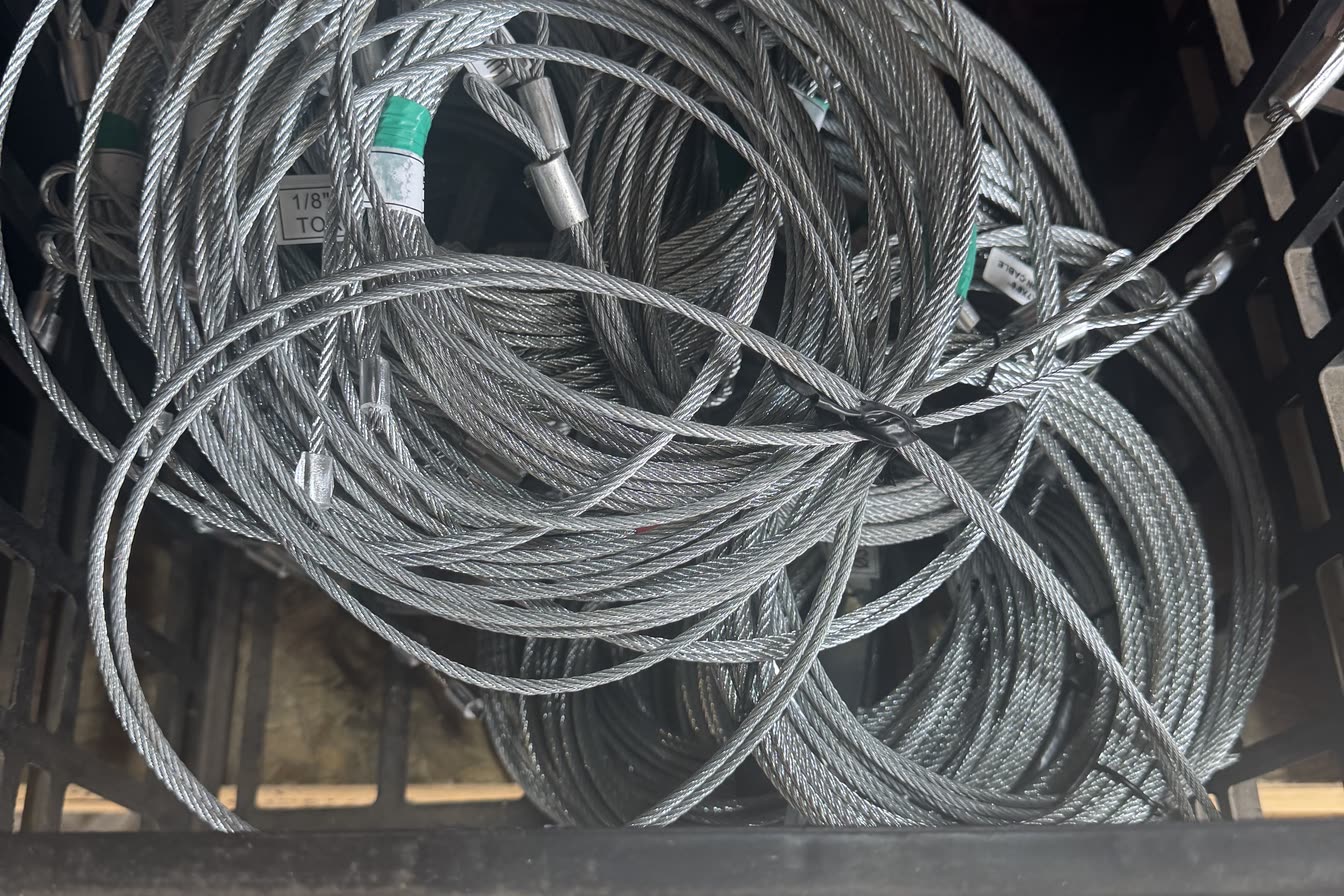 Coils of galvanised garage door lift cable in a crate, each cut to length with a swaged stop on the end and a tag