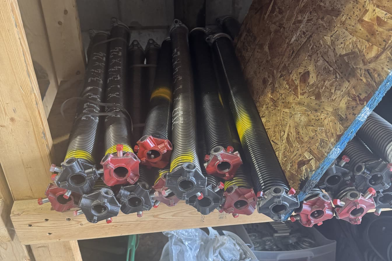 Torsion springs on a shop rack, each with its red and black winding cones fitted and paint-coded wire markings along the coils